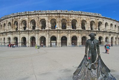 Vue des Arènes de Nimes et d'une statue de toreador