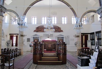 Tevah se situant au milieu de la synagogue Kahal shalom de Rhodes avec menoroth et chandeliers sous un arc